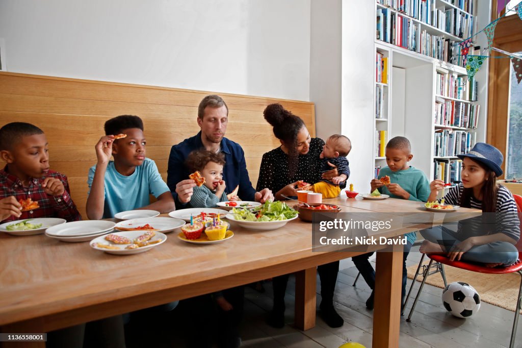 Large multi ethnic family having food at kitchen table