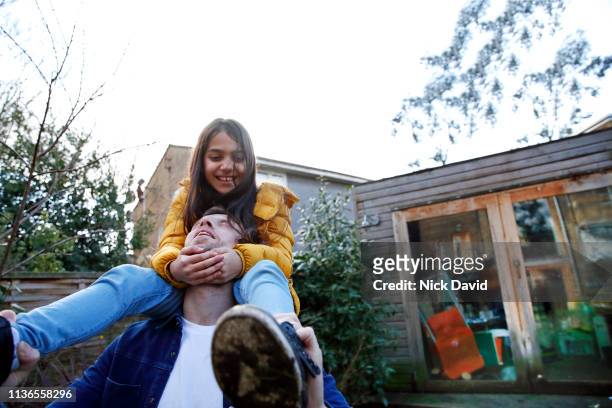 Father carrying daughter on shoulders in back yard