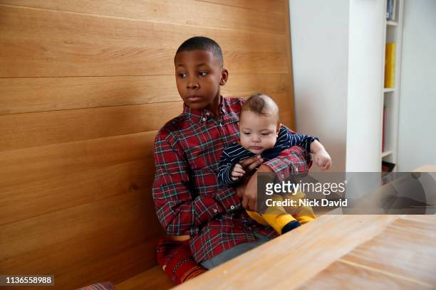 Boy holding baby brother at kitchen table