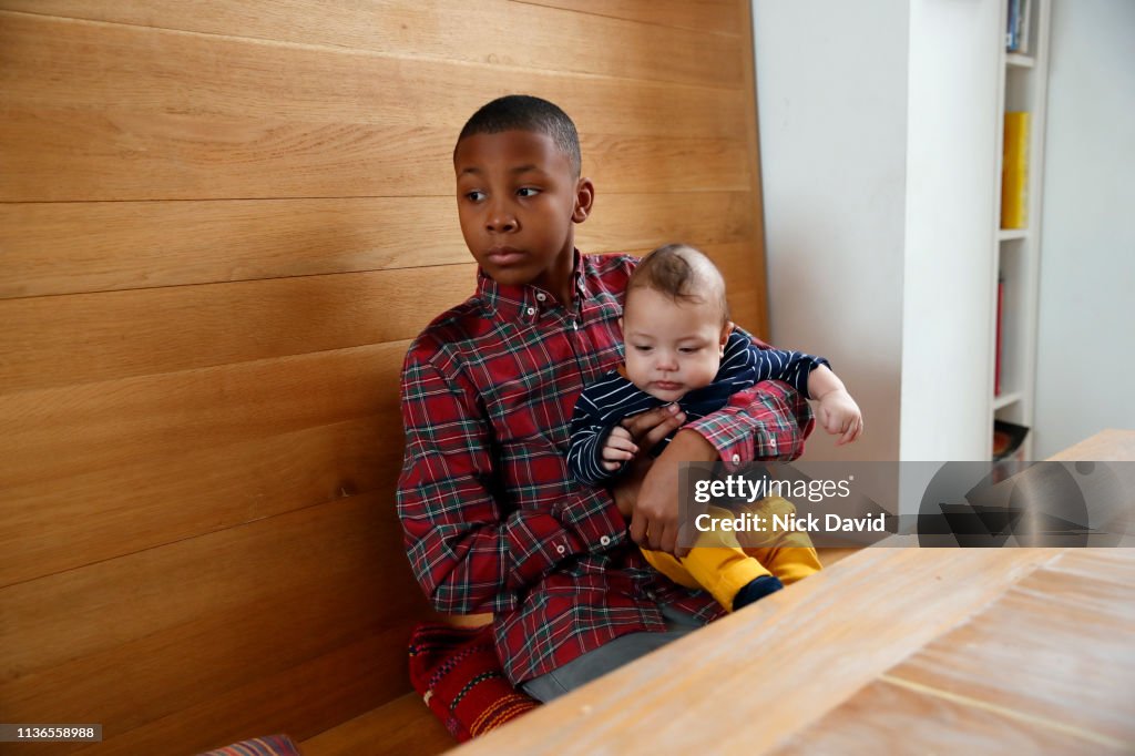 Boy holding baby brother at kitchen table