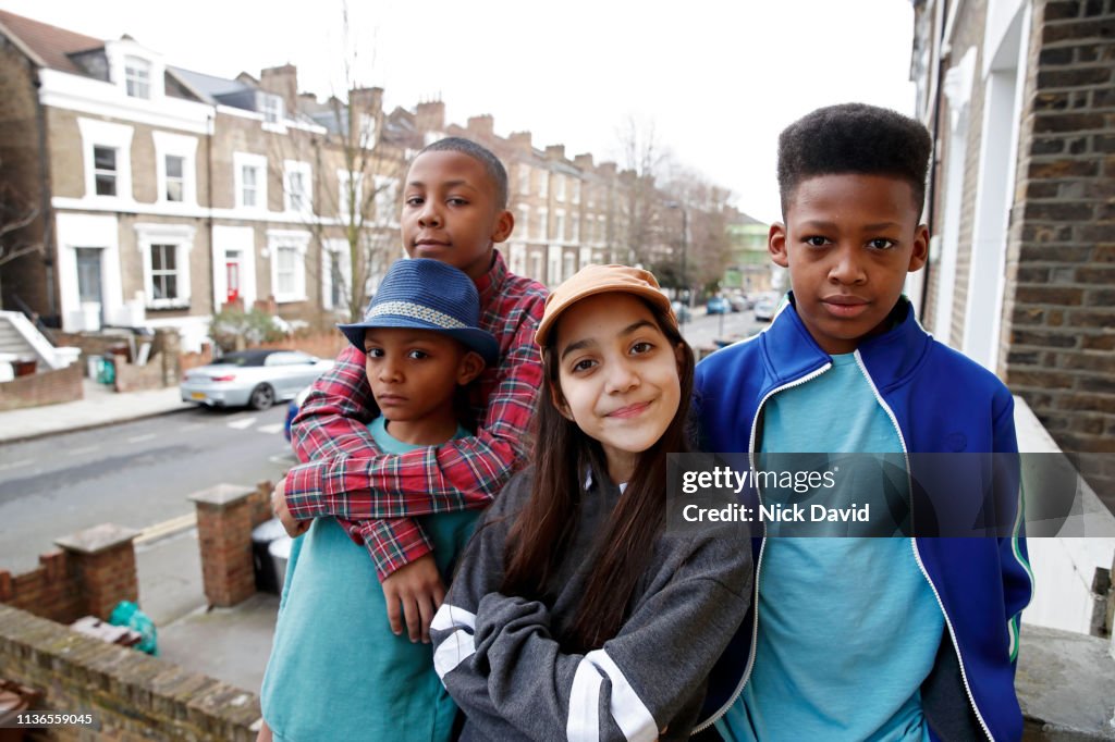 Multi ethnic siblings looking at camera outside townhouse