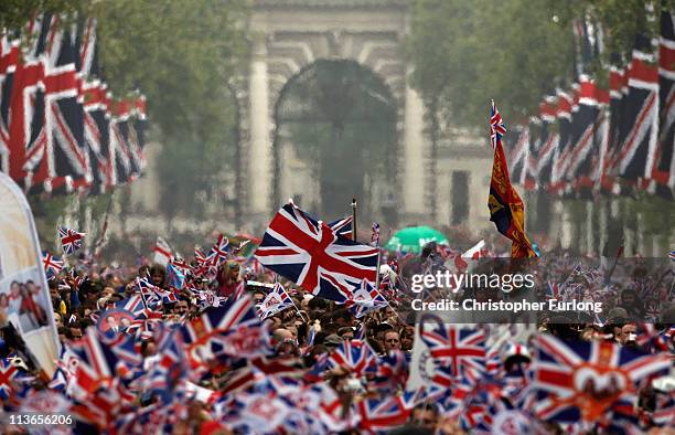 Well wishers wave flags as they surge along the Mall behind the police towards Buckingham Palace to celebrate the Royal Wedding of Prince William,...