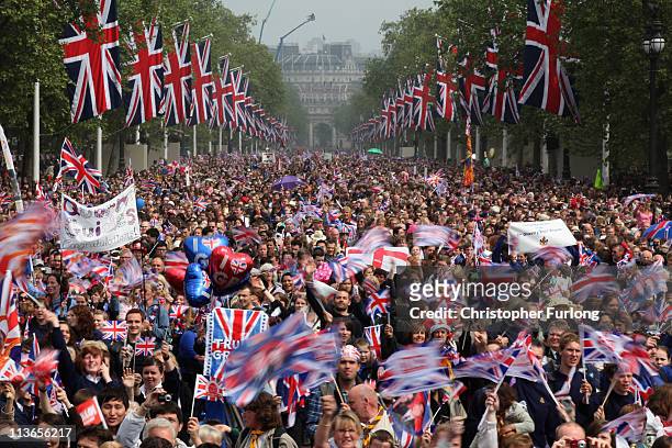 Well wishers wave flags as they surge along the Mall behind the police towards Buckingham Palace to celebrate the Royal Wedding of Prince William,...