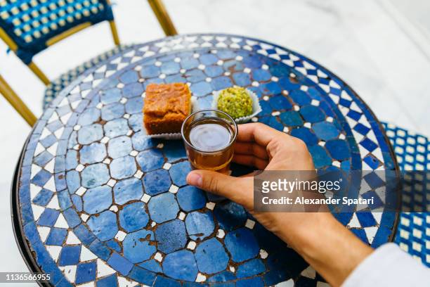 personal perspective of man drinking sweet tea with morrocan pastries at cafe - cafe culture stock-fotos und bilder