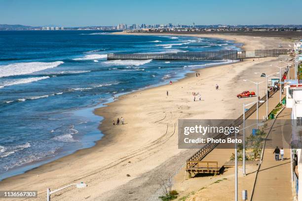 the us-mexico border wall at tijuana beach in baja california with the city of san diego on the horizon - tijuana mexico stock pictures, royalty-free photos & images