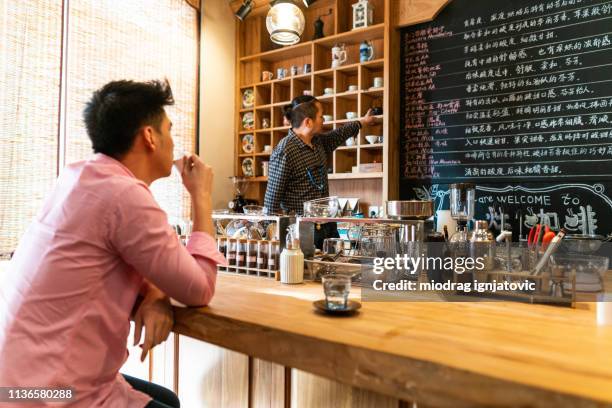 kellner empfiehlt kaffee für kunden - schürze mann rückansicht stock-fotos und bilder