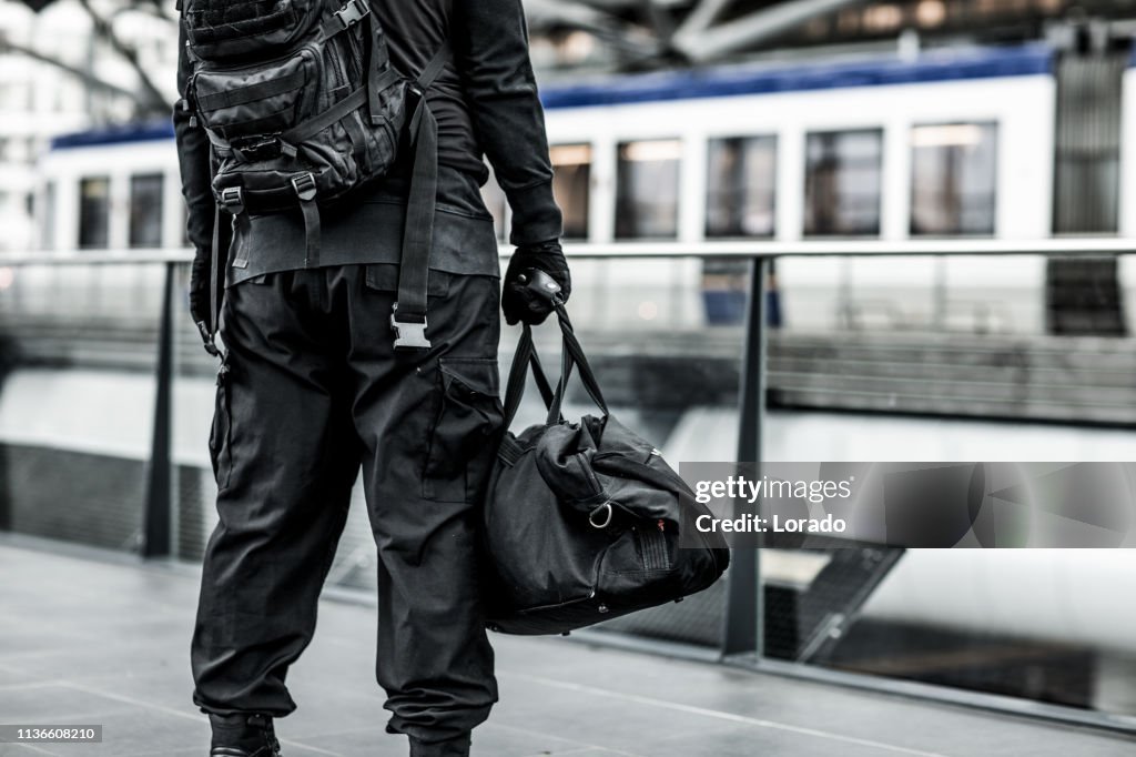 Dark hooded terrorist figure at public transport hub