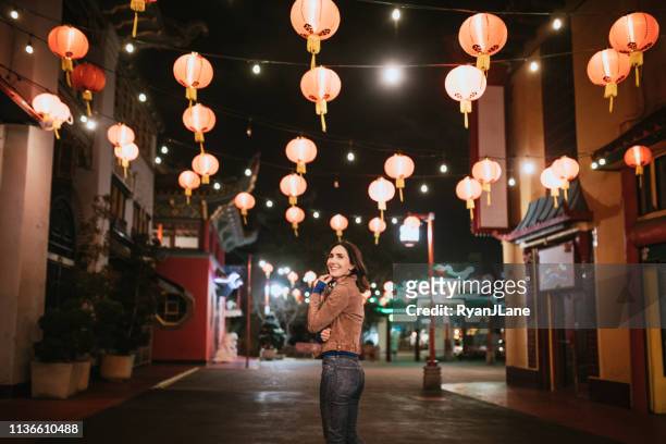 woman explores chinatown in downtown los angeles at night - chinatown stock pictures, royalty-free photos & images