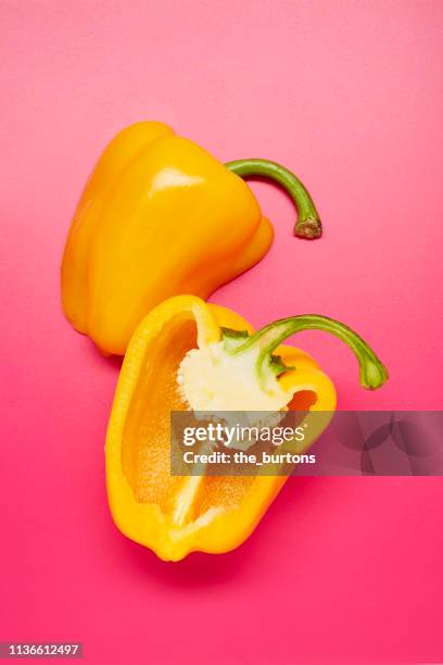 still life of sliced yellow bell peppers on pink background - gele paprika stockfoto's en -beelden