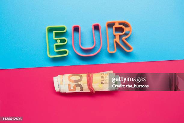 still life of eur letters and roll of euro banknotes - fajo de billetes de euro fotografías e imágenes de stock