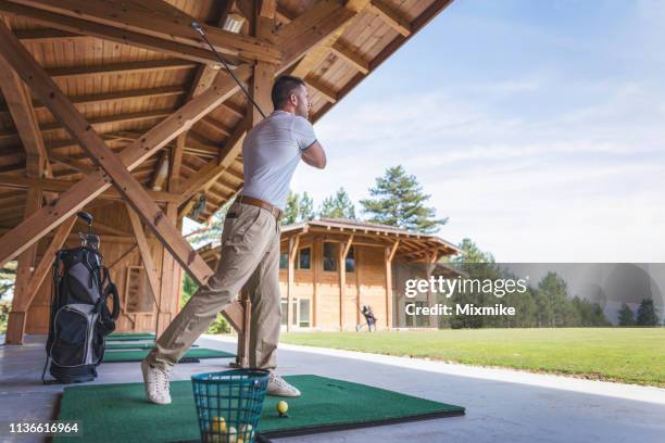 adult man taking a tee shot at the golf school - golf lessons stock pictures, royalty-free photos & images