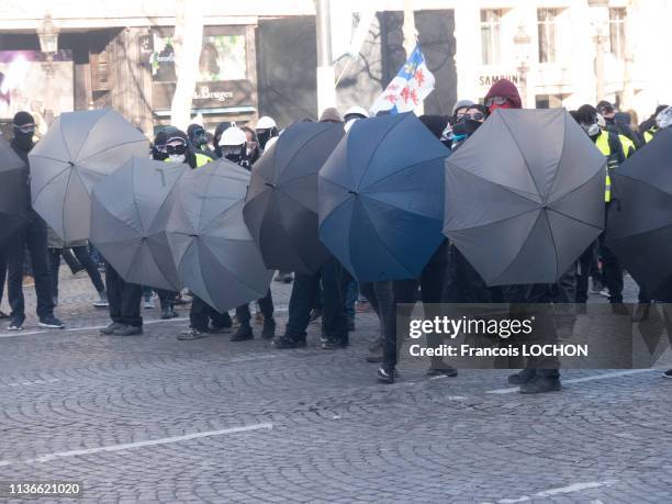 Casseurs black bloc cachés derrière des parapluies lors de la manifestation de l'acte 18 des "Gilets Jaunes" le 16 mars 2019 à Paris, France.