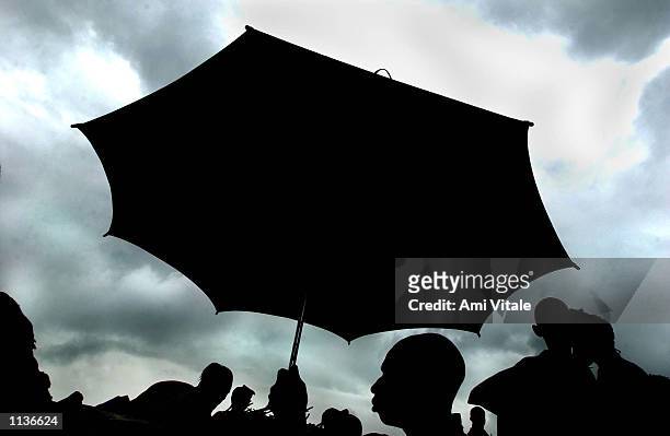 Person carrying an umbrella is shown silhouetted as the last Sierra Leonians who were being repatriated to their homes for the first time in 11 years...