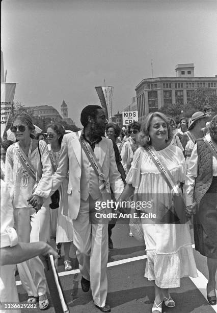 View of activists, from left, Gloria Steinem, Dick Gregory , and Betty Friedan as they hold hands on Pennsylvania Avenue during the Equal Rights...