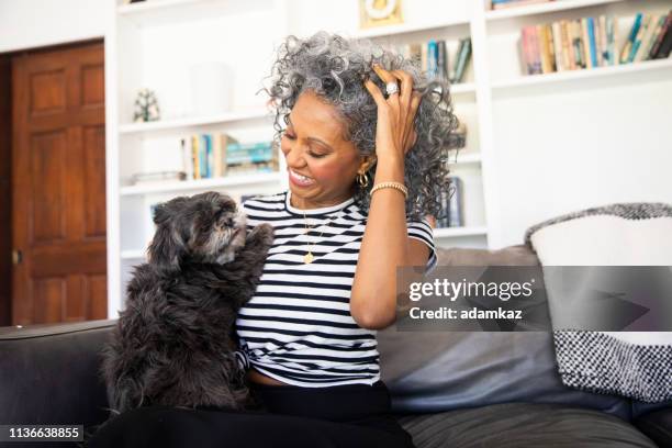 black woman cuddles with her dog at home - different pets stock pictures, royalty-free photos & images