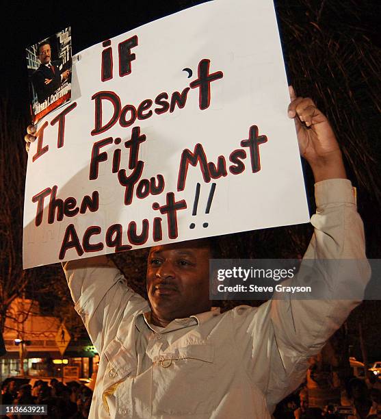 Najee Ali holds a placard with a statement "If it doesn't fit you must then you must acquit" made famous by the late attorney Johnnie L. Cochran at a...