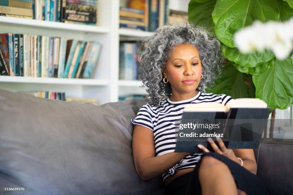 Black Woman Reading a book in her library at home