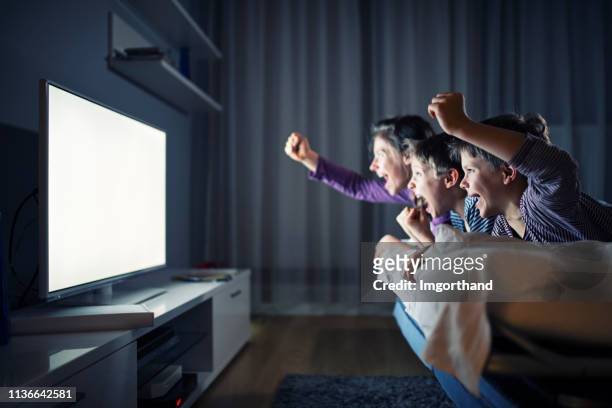 drei kinder schauen fern und jubeln - begeistert fernsehen stock-fotos und bilder