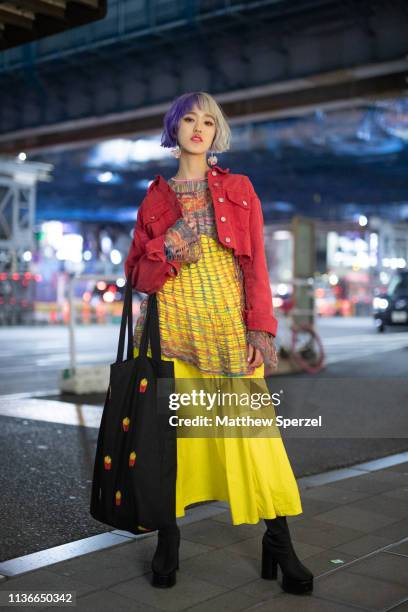 Guest is seen wearing red jacket, yellow pattern top, yellow skirt and black heels and black fry print tote bag during the Amazon Fashion Week TOKYO...