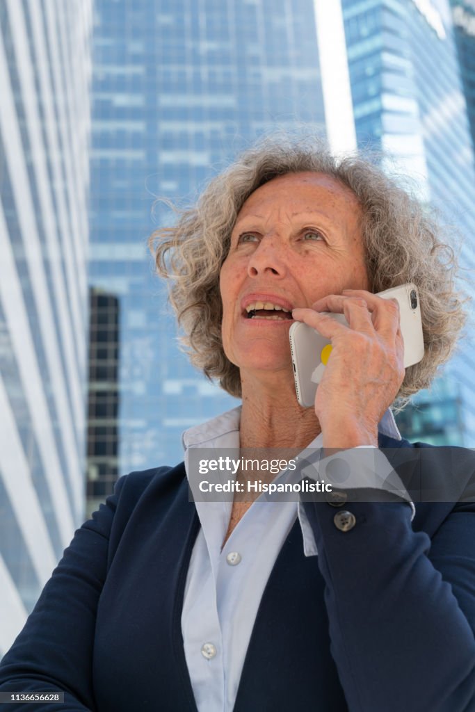 Senior woman on a phone call at a business district looking serious