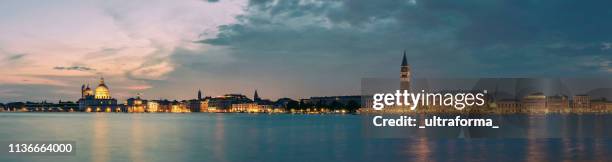 panoramisch uitzicht op de verlichte punta dogana santa maria della salute en san marcoplein in venetië 's nachts - riva stockfoto's en -beelden
