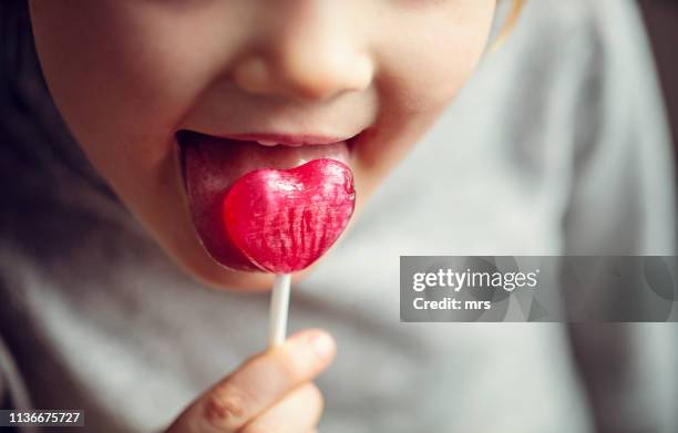 child eating a lollipop - girls licking girls stockfoto's en -beelden