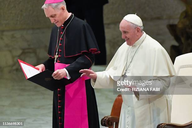 Pope Francis gestures alongside Prefect of the Papal Household, Georg Gaenswein at the start of an audience with students of Rome's Visconti high...