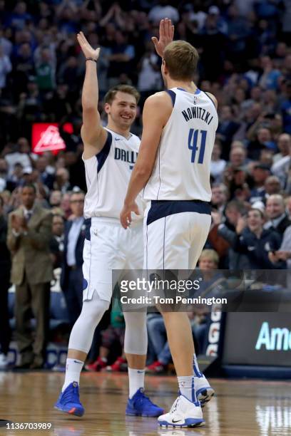 Dirk Nowitzki of the Dallas Mavericks celebrates with Luka Doncic of the Dallas Mavericks after scoring a basket against Kenrich Williams of the New...