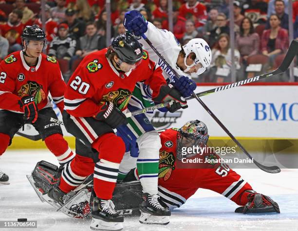 Corey Crawford of the Chicago Blackhawks knocks the puck away on a shot by Loui Eriksson of the Vancouver Canucks as Brandon Saad defends at the...