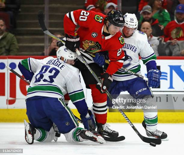 Brandon Saad of the Chicago Blackhawks forces his way between Jay Beagle and Alex Biega of the Vancouver Canucks at the United Center on March 18,...