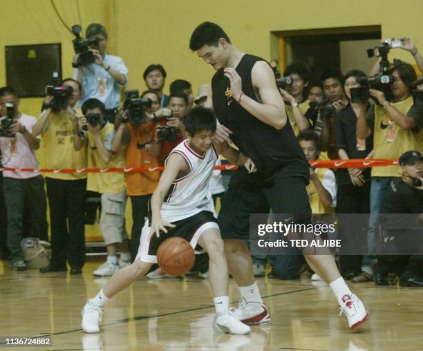 Yao Ming of the Houston Rockets plays with a young enthusiast during a demonstration game in Hong Kong, 05 August 2003. Yao is here to play in an...