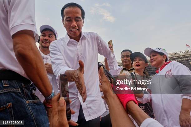 Indonesian President Joko Widodo, popularly known as Jokowi, shakes hands with supporters at a rally at Jakarta's main stadium on April 13, 2019 in...