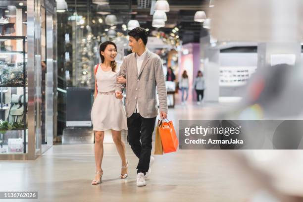 young chinese couple in the shopping centre - chinese young adults shopping imagens e fotografias de stock