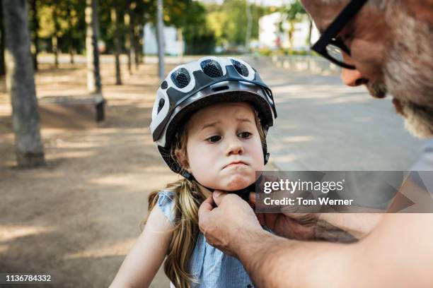 grandpa doing up granddaughter's crash helmet - cycling helmet stock-fotos und bilder