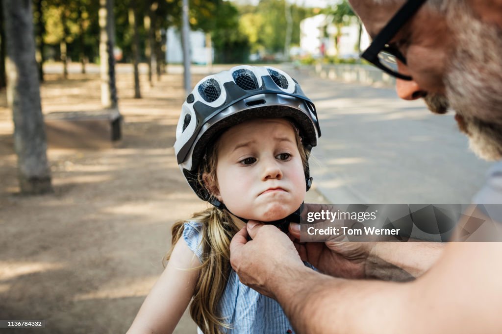 Grandpa Doing Up Granddaughter's Crash Helmet