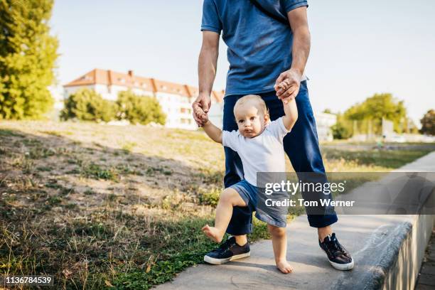 grandpa helping young grandson walk - baby walk stock-fotos und bilder