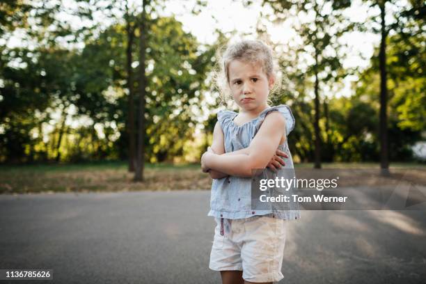 young girl with arms folder at the park - caprice photos et images de collection