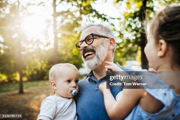 grandchildren having fun with grandpa at the park - baby accessories the dummy stock pictures, royalty-free photos & images