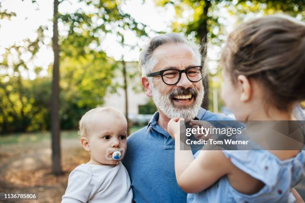 grandfather having fun with grandchildren at the park - kind brille stock-fotos und bilder