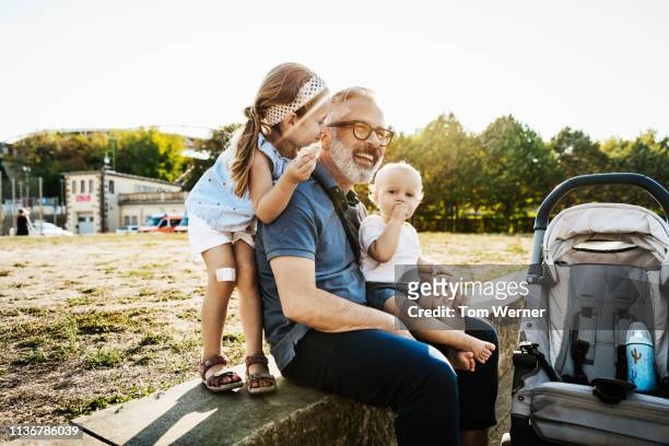 kids playing with grandpa at the park - weitersagen stock-fotos und bilder