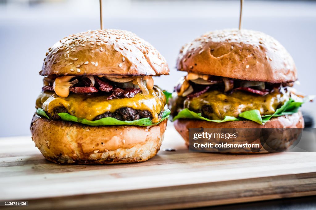 Freshly flame grilled bacon cheese burgers in a row
