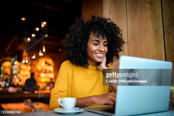 smiling woman using laptop at the bar. - internet cafe stock pictures, royalty-free photos & images