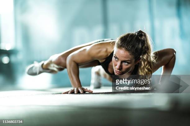 young female athlete exercising push-ups with in a gym. - endurance training stock pictures, royalty-free photos & images