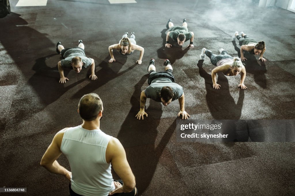 Athletic people doing push-ups on sports training with their coach.