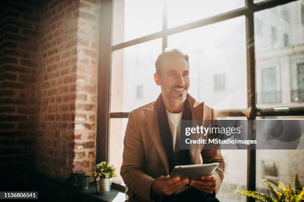 smiling mature mann using digital tablet. - business mann ipad stock pictures, royalty-free photos & images