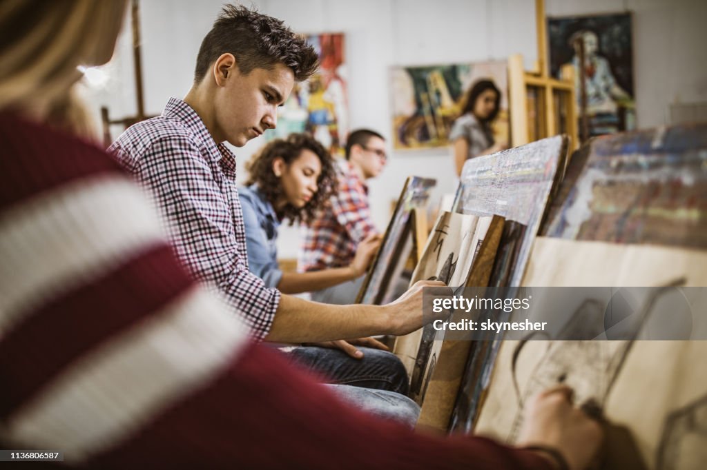 Group of art students drawing paintings at art studio.