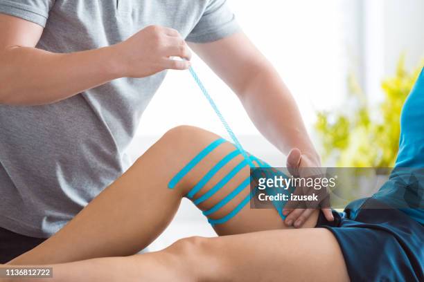 kinesio taping on woman's knee - kinesiotape stock pictures, royalty-free photos & images