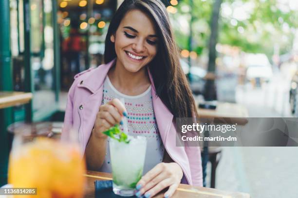 teenage girl drinking mojito cocktail at sidewalk cafe - mojito stock pictures, royalty-free photos & images