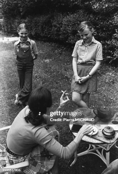 Femme prenant le thé avec ses filles dans un jardin, dans les années 1980, France.