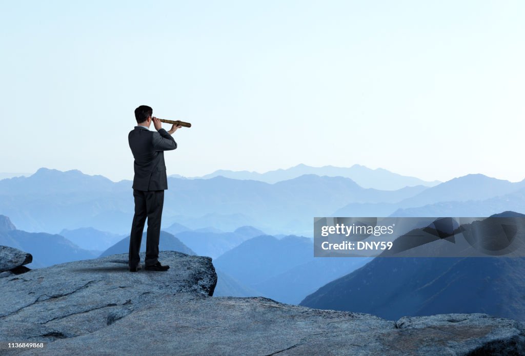 Businessman With Spyglass Looking Out Toward Mountain Range